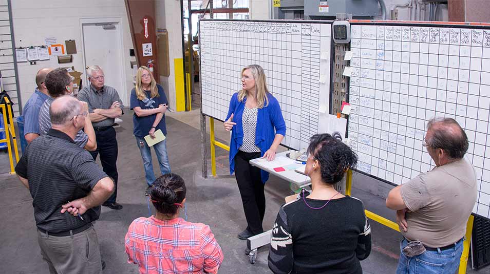 EJ employees standing during a production review meeting at Muskeegon Composites manufacturing facility.