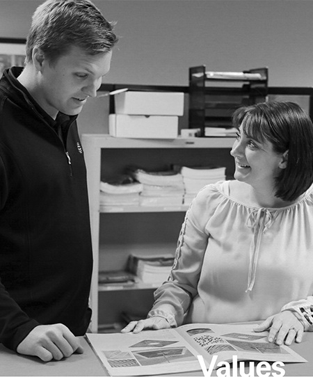 EJ Values man and woman working in office looking at catalog