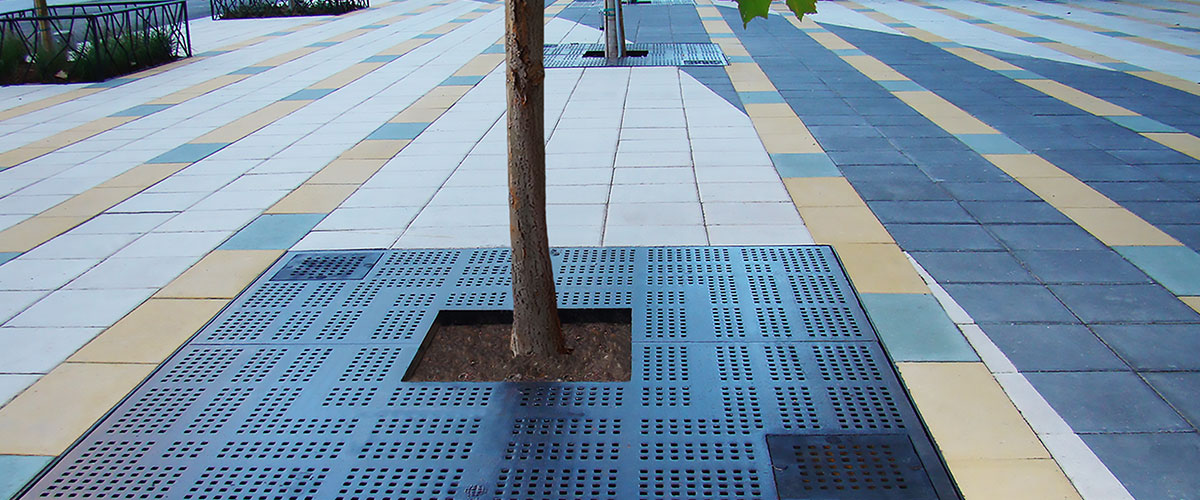 EJ Manhattan design cast iron tree grate installed in colored brick sidewalk